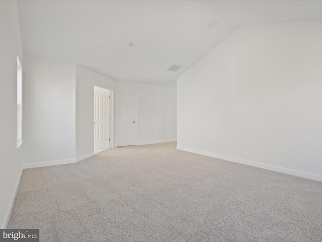 unfurnished room featuring lofted ceiling and light colored carpet