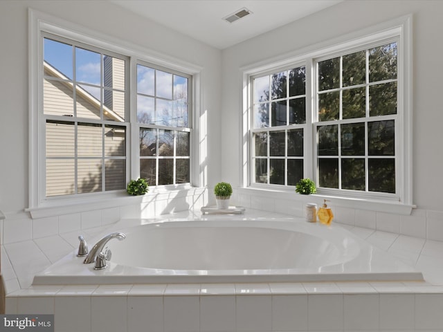 bathroom featuring a relaxing tiled tub and a healthy amount of sunlight