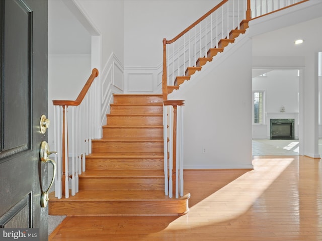 staircase with a premium fireplace and wood-type flooring