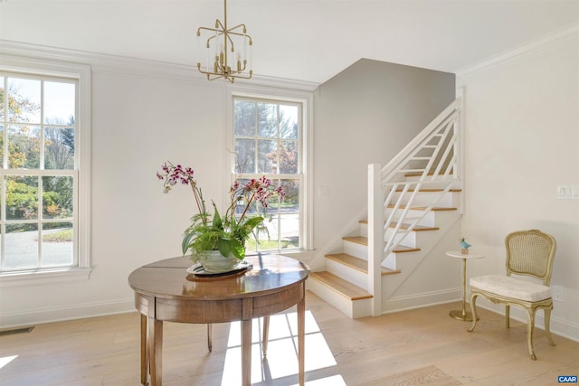 interior space with plenty of natural light, ornamental molding, hardwood / wood-style floors, and a notable chandelier