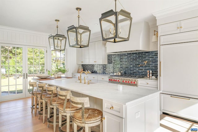 kitchen featuring white cabinets, high quality appliances, a center island with sink, and sink