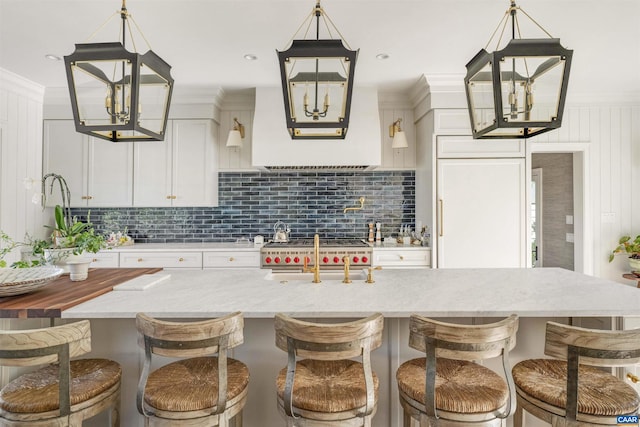 kitchen featuring decorative light fixtures, decorative backsplash, a kitchen breakfast bar, and white cabinetry