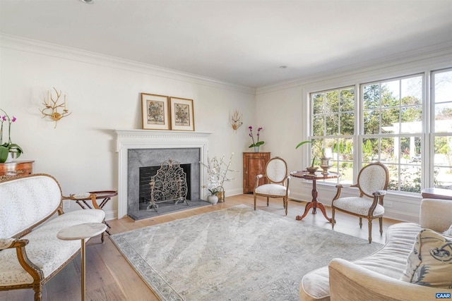 living room with a high end fireplace, crown molding, and light hardwood / wood-style flooring