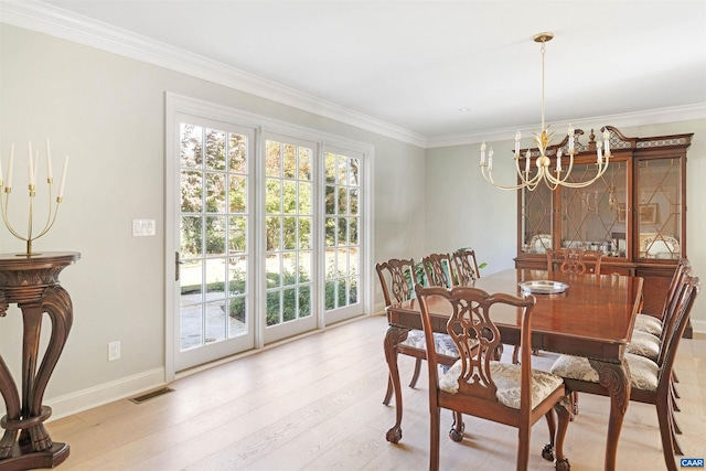 dining space with light hardwood / wood-style floors, ornamental molding, and a notable chandelier