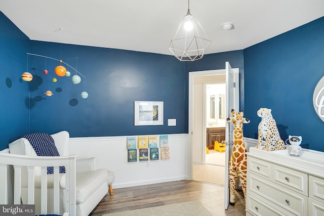 bedroom featuring light wood finished floors and wainscoting