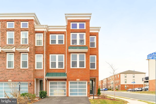 multi unit property featuring driveway, an attached garage, and brick siding