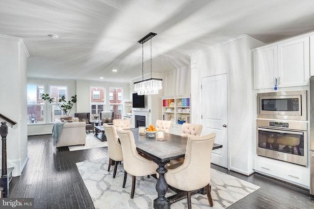 dining area with baseboards, a fireplace, dark wood finished floors, and a notable chandelier