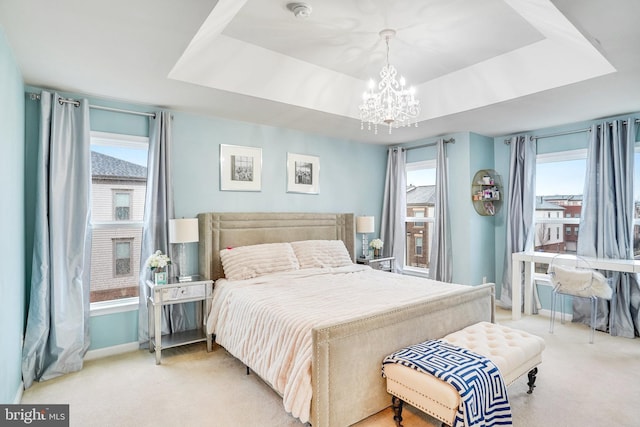 carpeted bedroom with multiple windows, baseboards, a raised ceiling, and a chandelier