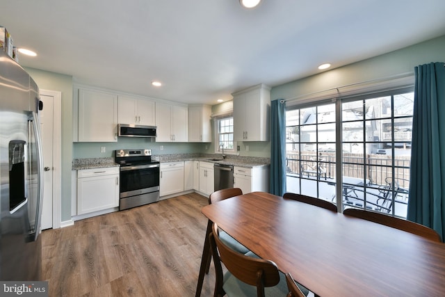 kitchen with white cabinets, light stone countertops, appliances with stainless steel finishes, and sink