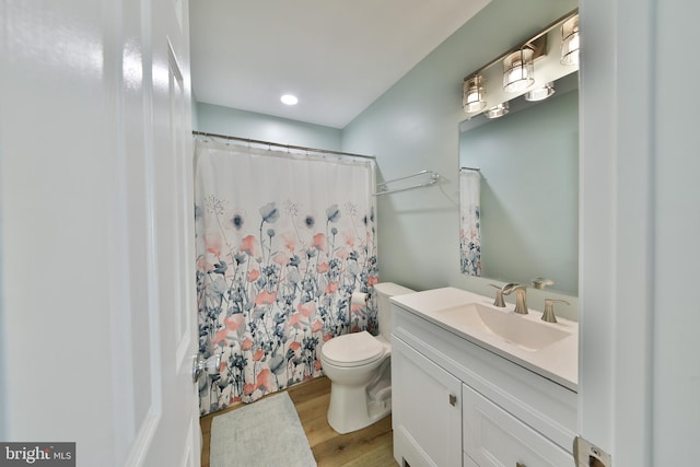 bathroom featuring hardwood / wood-style flooring, toilet, vanity, and a shower with curtain