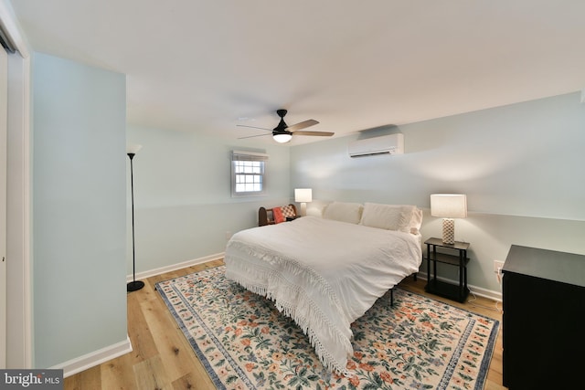 bedroom featuring light wood-type flooring, a wall mounted air conditioner, and ceiling fan