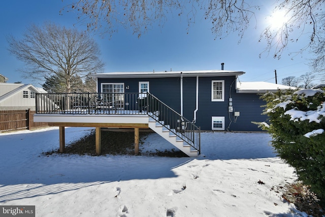 snow covered rear of property with a wooden deck