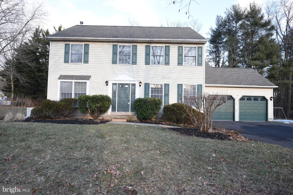 colonial home featuring a garage and a front yard