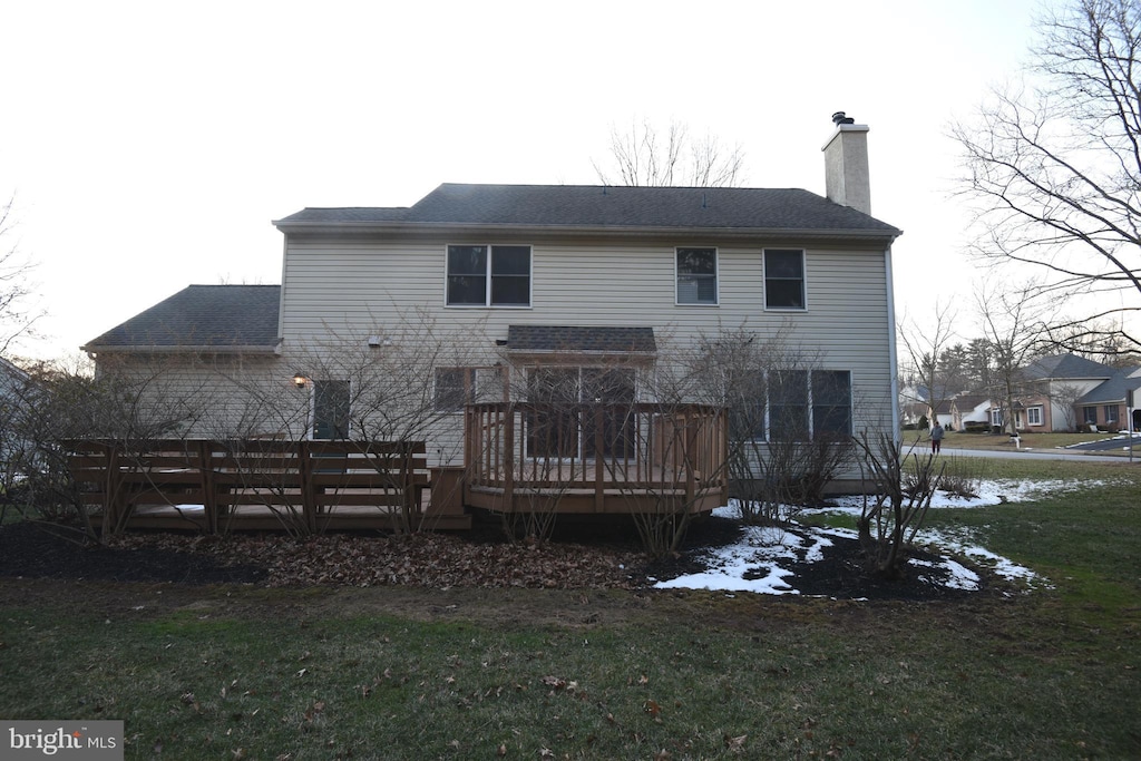 rear view of property featuring a deck and a yard