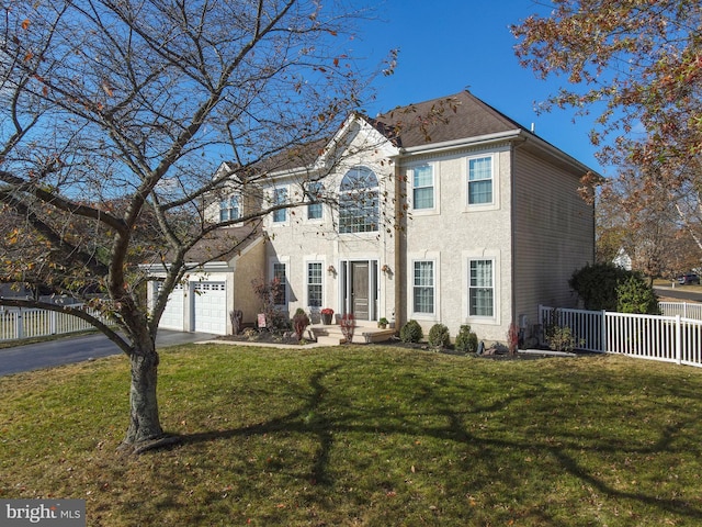 colonial home with a front lawn, fence, aphalt driveway, stucco siding, and an attached garage