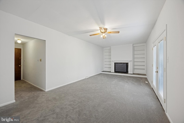 unfurnished living room with ceiling fan, built in shelves, and carpet flooring