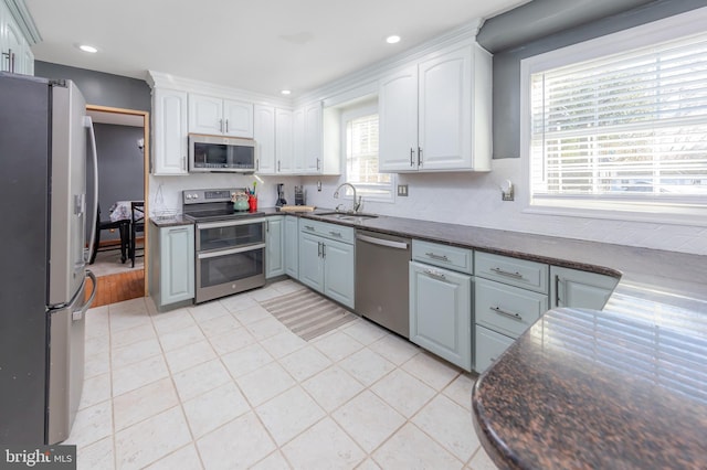 kitchen with stainless steel appliances, white cabinets, sink, and plenty of natural light