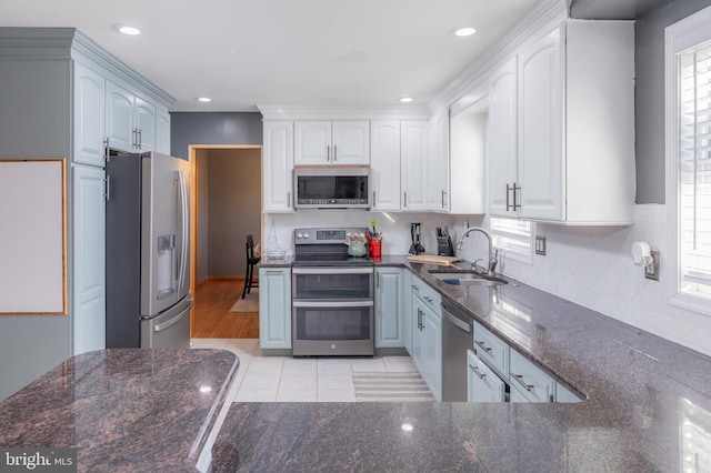 kitchen featuring white cabinets, stainless steel appliances, light tile patterned floors, a wealth of natural light, and sink