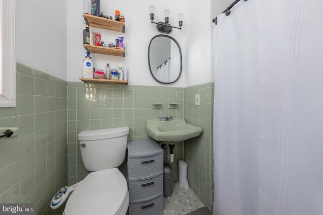 bathroom with tile walls, walk in shower, sink, and toilet