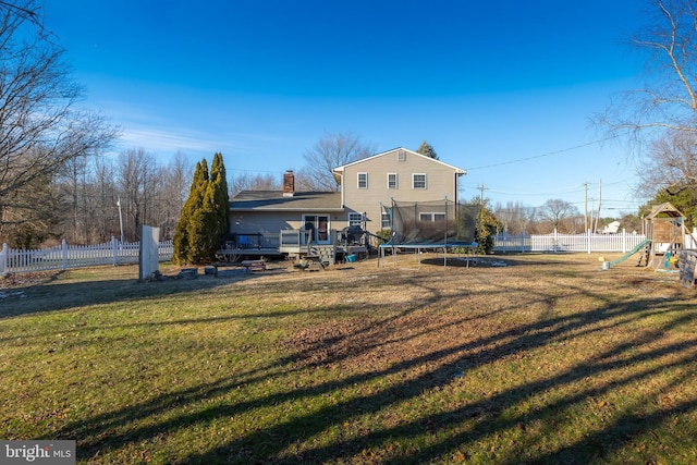 back of house with a yard, a wooden deck, a playground, and a trampoline