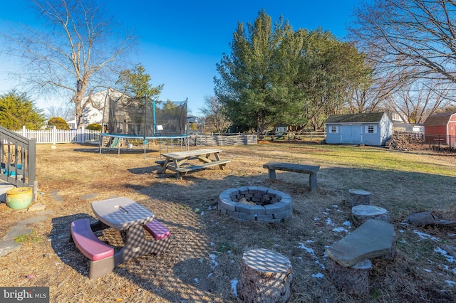 view of yard with a fire pit, a trampoline, and a storage shed