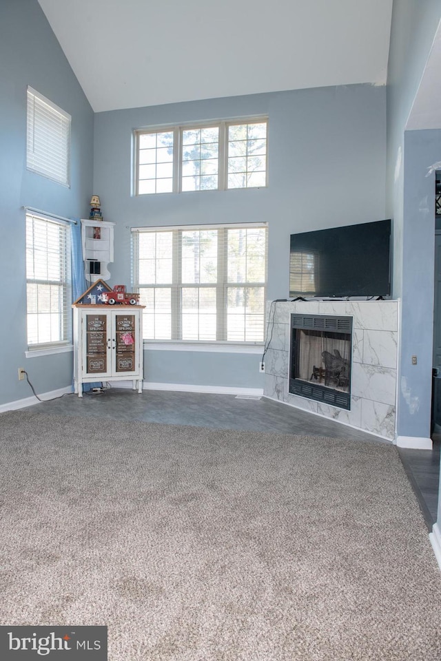 living room featuring high vaulted ceiling, carpet floors, a tiled fireplace, and baseboards