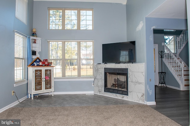 living area featuring stairs, a high ceiling, a fireplace, and a wealth of natural light