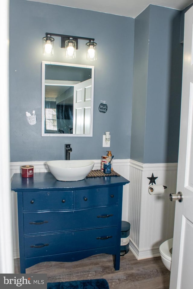 bathroom featuring a wainscoted wall, vanity, toilet, and wood finished floors