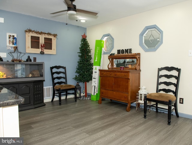 sitting room with visible vents, ceiling fan, baseboards, and wood finished floors