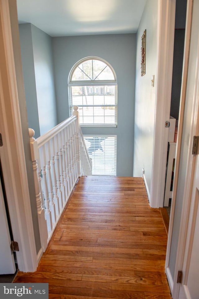 corridor with wood finished floors and an upstairs landing