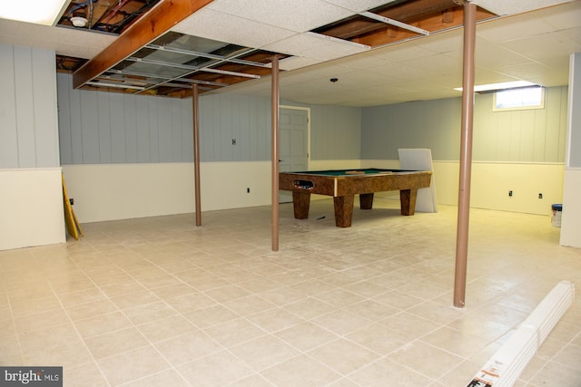 basement with a paneled ceiling and wooden walls