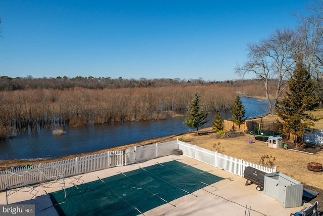 view of pool with a patio area, a trampoline, a water view, and fence