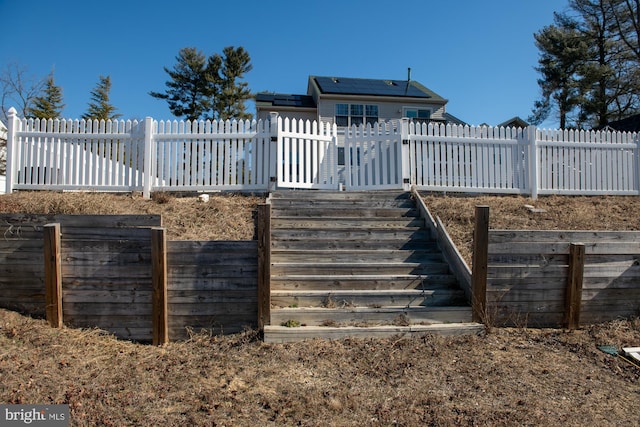 back of house featuring a fenced backyard and solar panels