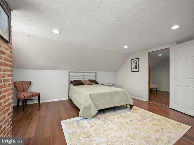 bedroom with dark hardwood / wood-style floors, a textured ceiling, and lofted ceiling