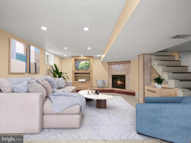 living room featuring built in features, a tile fireplace, and light tile patterned floors