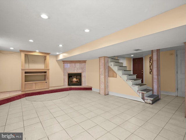 basement with a tile fireplace and light tile patterned flooring