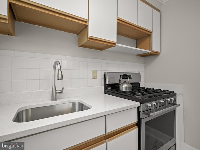 kitchen with sink, white cabinets, stainless steel range with gas stovetop, and light stone countertops