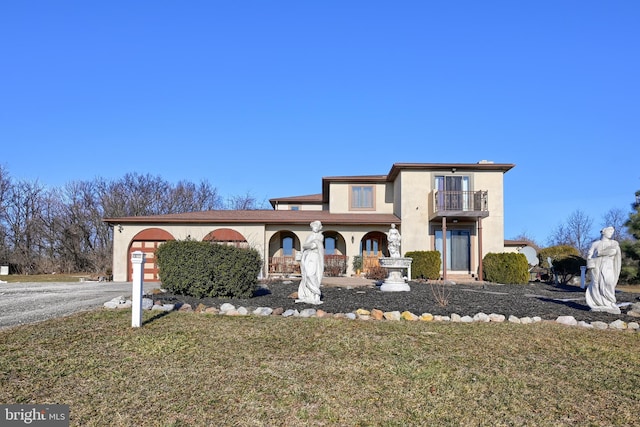 view of front facade featuring a garage, a front yard, and a balcony