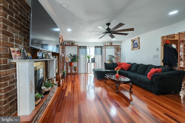 living room featuring wood-type flooring, ceiling fan, and a fireplace