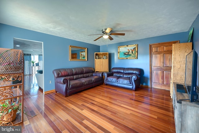 living room featuring ceiling fan, wood-type flooring, and a textured ceiling