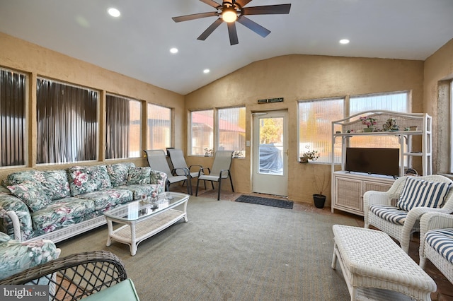 carpeted living room with ceiling fan and vaulted ceiling