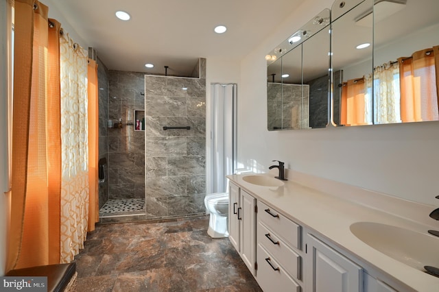 bathroom with vanity, plenty of natural light, a tile shower, and toilet