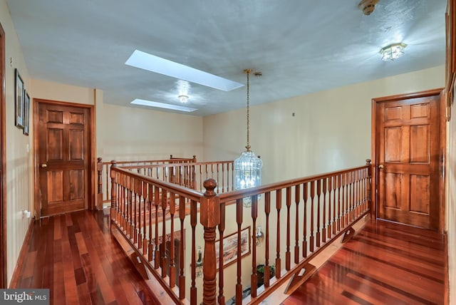 hall with dark wood-type flooring and a skylight