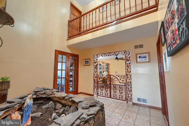 living room with a high ceiling, light tile patterned flooring, ceiling fan, and french doors