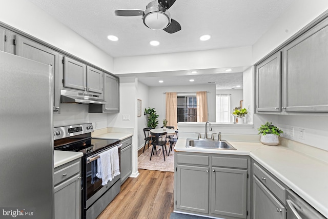 kitchen with a textured ceiling, appliances with stainless steel finishes, light hardwood / wood-style floors, sink, and gray cabinets