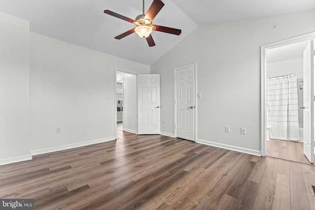 unfurnished bedroom featuring ceiling fan, connected bathroom, dark hardwood / wood-style floors, and vaulted ceiling