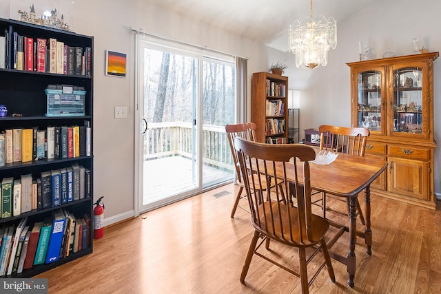 dining area with light hardwood / wood-style floors and a chandelier