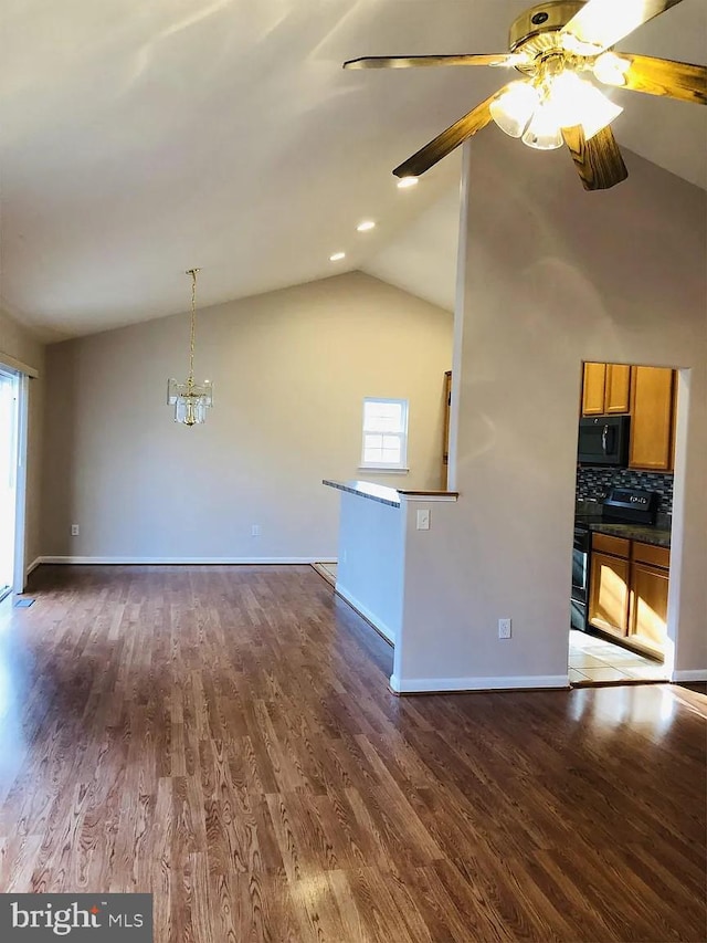 interior space featuring black appliances, vaulted ceiling, dark hardwood / wood-style floors, ceiling fan with notable chandelier, and backsplash