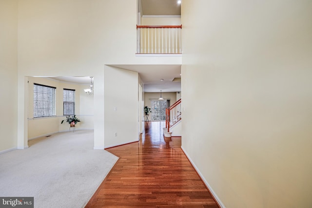 corridor featuring hardwood / wood-style flooring, a chandelier, and a high ceiling