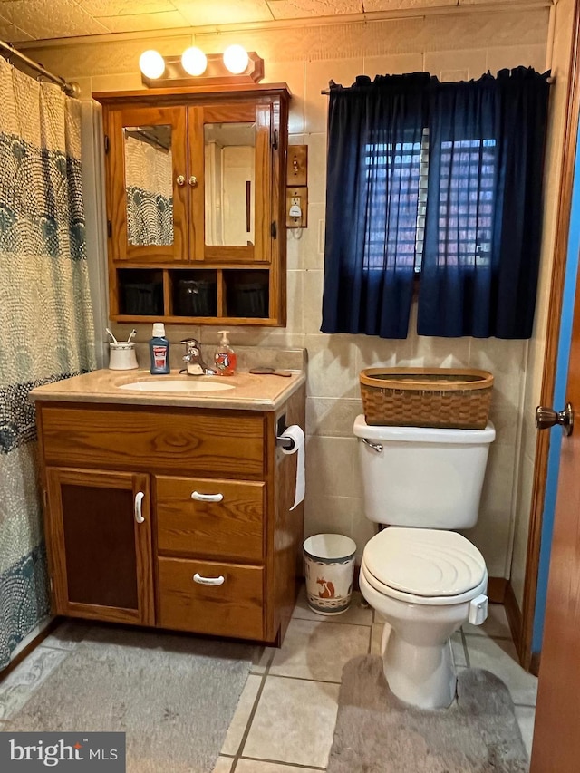 bathroom featuring tile patterned flooring, toilet, vanity, a shower with curtain, and tile walls